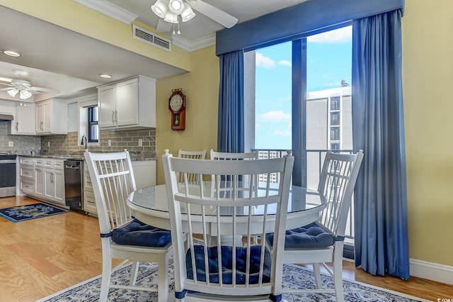 dining area featuring ceiling fan, light wood-type flooring, and crown molding