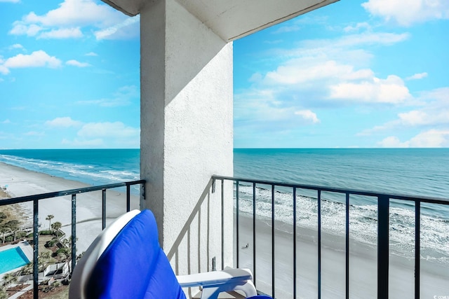 balcony with a water view and a view of the beach