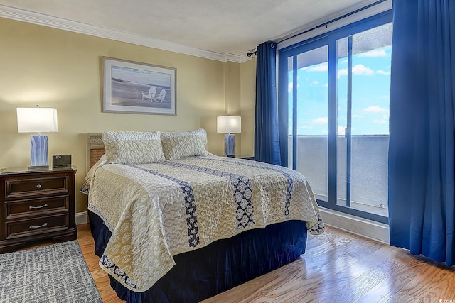 bedroom with crown molding, light hardwood / wood-style flooring, and access to exterior