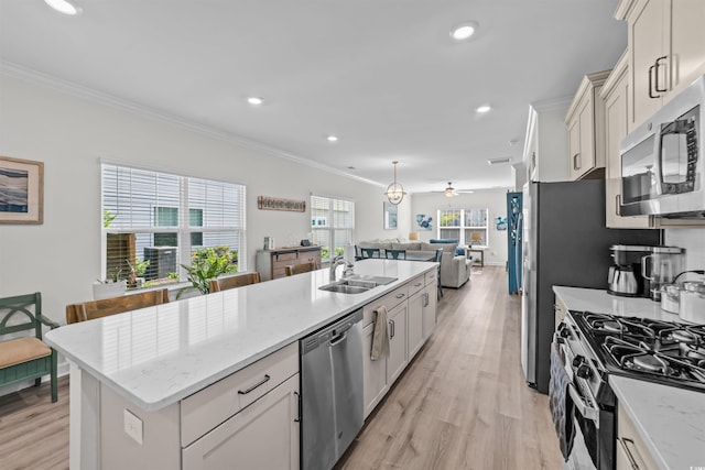 kitchen with light hardwood / wood-style floors, an island with sink, light stone counters, stainless steel appliances, and crown molding