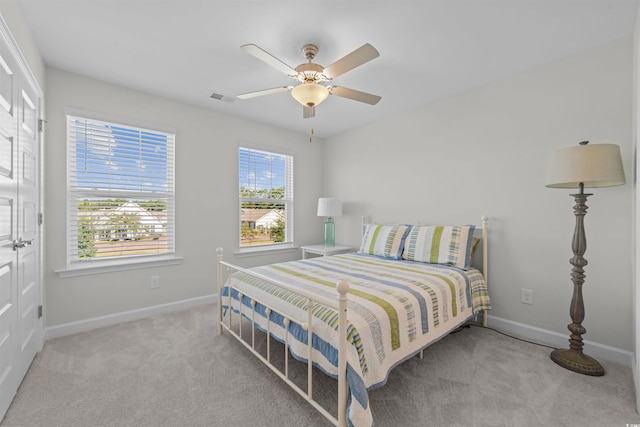 carpeted bedroom with multiple windows and ceiling fan