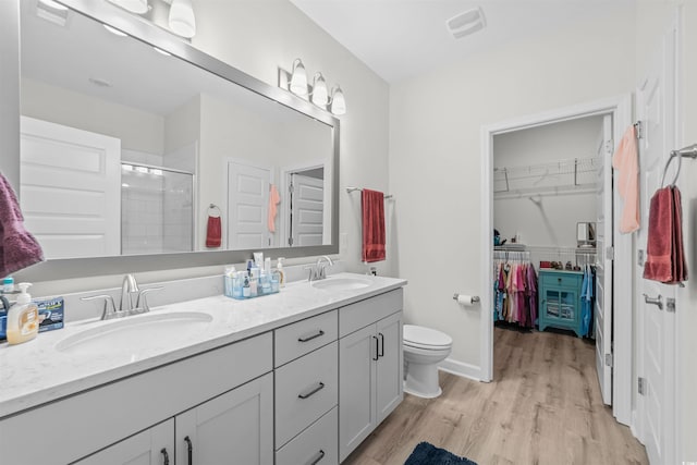 bathroom featuring walk in shower, wood-type flooring, vanity, and toilet