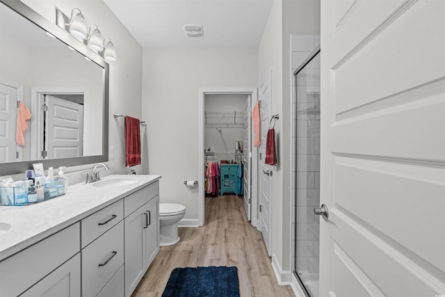 bathroom with walk in shower, wood-type flooring, vanity, and toilet