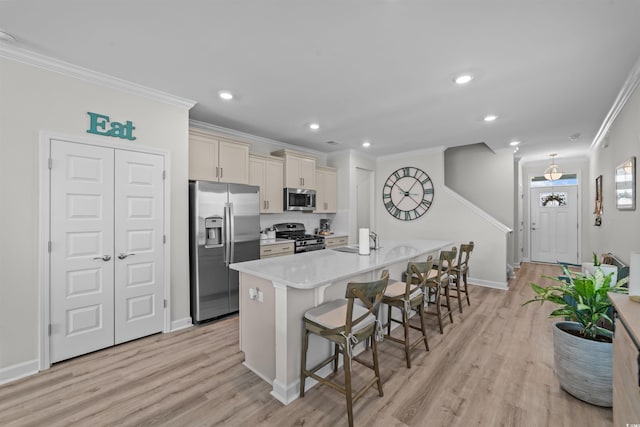 kitchen featuring sink, a center island with sink, appliances with stainless steel finishes, a breakfast bar, and light hardwood / wood-style floors