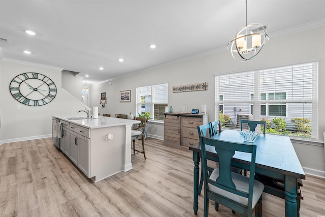 kitchen with decorative light fixtures, an island with sink, light wood-type flooring, and ornamental molding