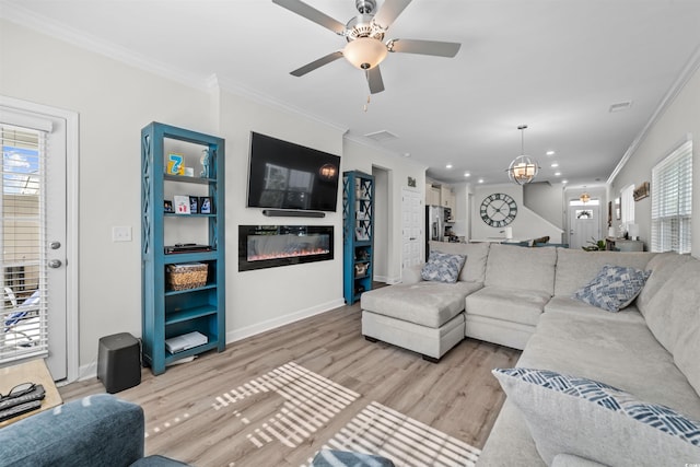 living room with ceiling fan with notable chandelier, light hardwood / wood-style flooring, and crown molding