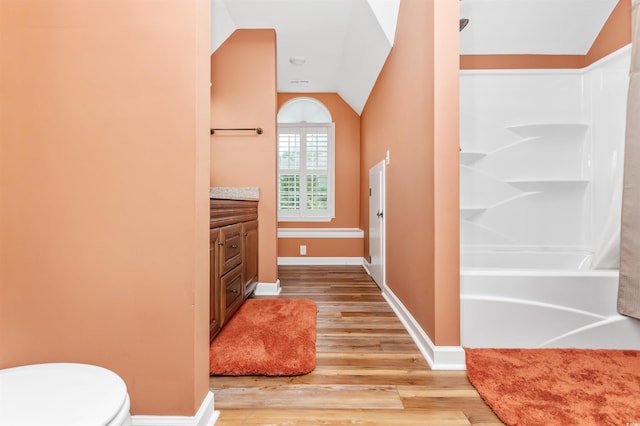 bathroom with lofted ceiling, vanity, toilet, and hardwood / wood-style flooring