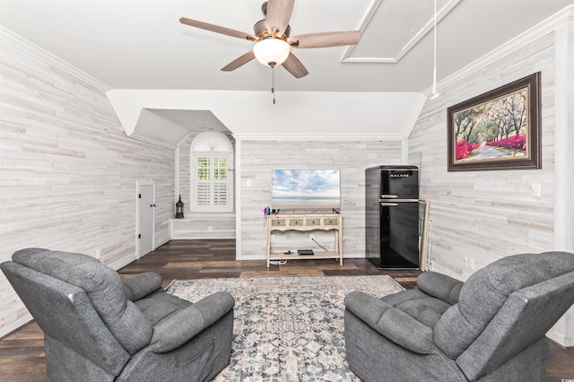 living room with vaulted ceiling, dark wood-type flooring, ornamental molding, ceiling fan, and wooden walls