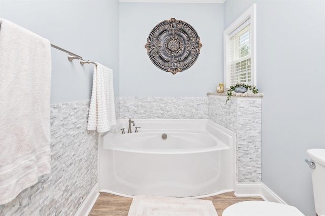 bathroom featuring a tub to relax in, toilet, and hardwood / wood-style flooring