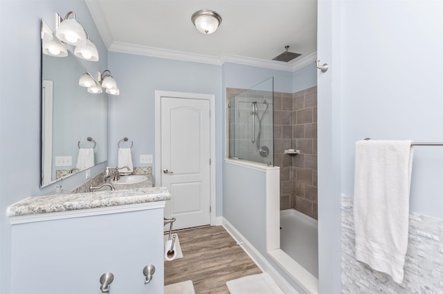 bathroom featuring wood-type flooring, crown molding, vanity, and tiled shower