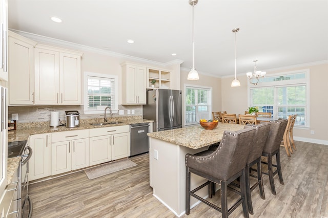 kitchen with hanging light fixtures, a kitchen island, stainless steel appliances, sink, and a chandelier