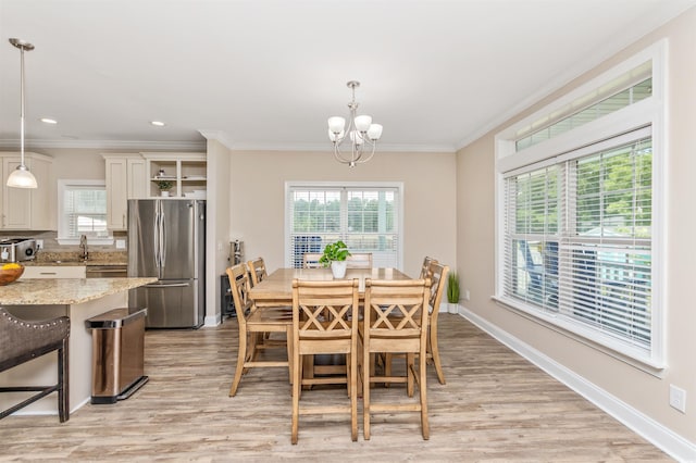 dining space with crown molding, sink, light hardwood / wood-style flooring, and a notable chandelier