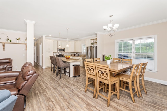 dining area with a notable chandelier, light hardwood / wood-style floors, and ornamental molding