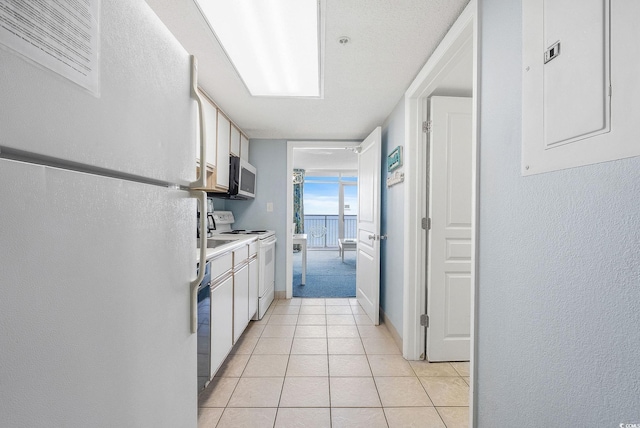 kitchen featuring white cabinets, electric panel, light tile patterned floors, and white appliances