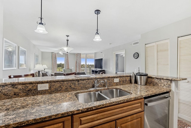 kitchen featuring ceiling fan, sink, stainless steel dishwasher, decorative light fixtures, and dark stone counters