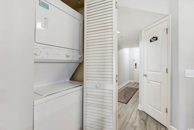 laundry area with light hardwood / wood-style flooring and stacked washer and dryer