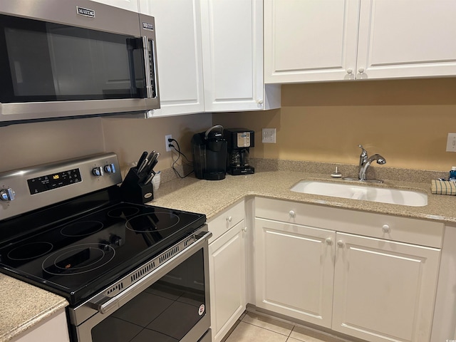 kitchen with light tile patterned floors, white cabinets, stainless steel appliances, and sink