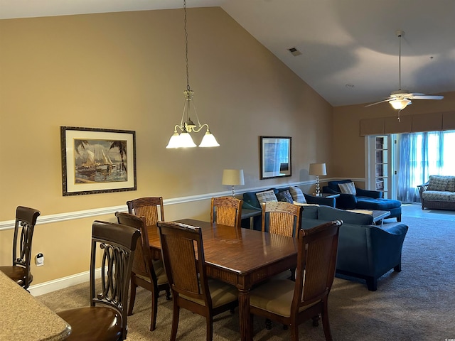 dining room featuring ceiling fan with notable chandelier, carpet flooring, and high vaulted ceiling