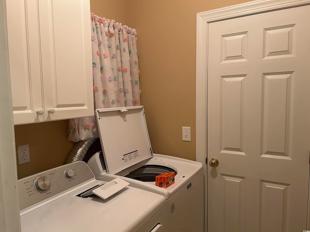 laundry area with washing machine and clothes dryer and cabinets