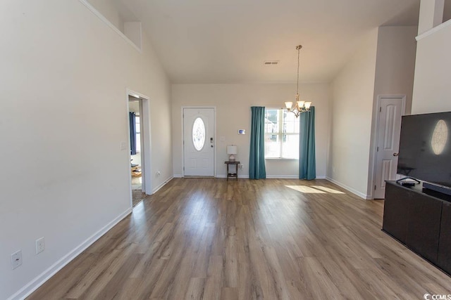 entryway with a chandelier, light wood-type flooring, and high vaulted ceiling