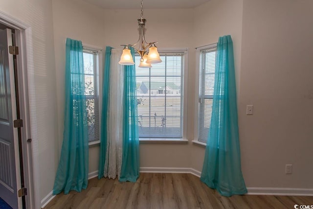 unfurnished dining area featuring an inviting chandelier and hardwood / wood-style flooring