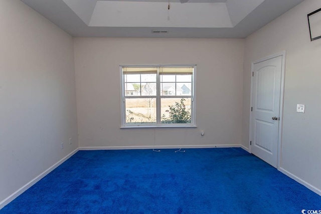 spare room featuring dark colored carpet and a tray ceiling