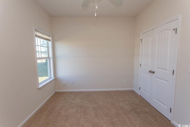 spare room featuring light colored carpet and ceiling fan