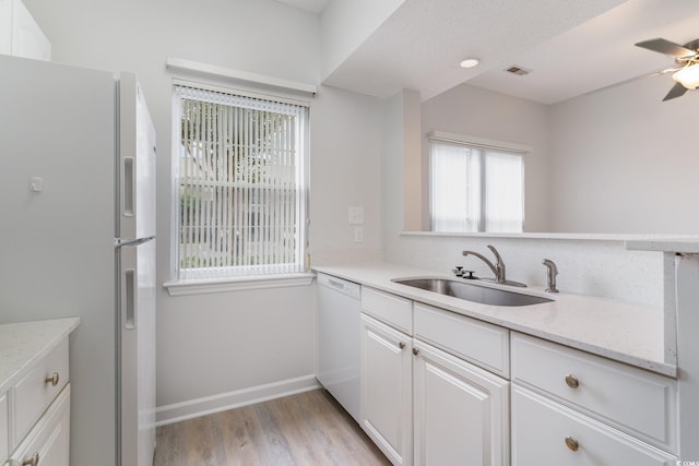 kitchen with a sink, white cabinetry, white appliances, visible vents, and ceiling fan