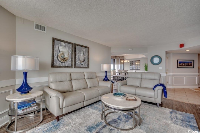 living room featuring a notable chandelier, a textured ceiling, and hardwood / wood-style floors