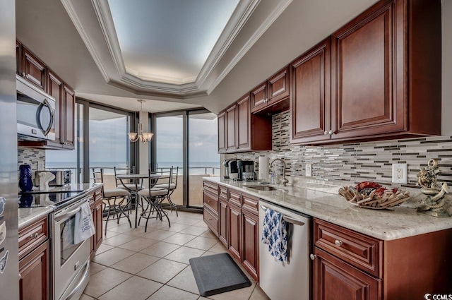 kitchen featuring appliances with stainless steel finishes, hanging light fixtures, decorative backsplash, a raised ceiling, and sink