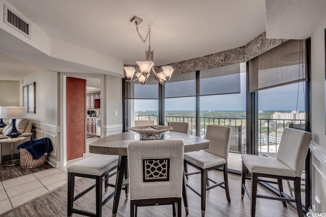 dining area featuring a textured ceiling, hardwood / wood-style floors, and a notable chandelier