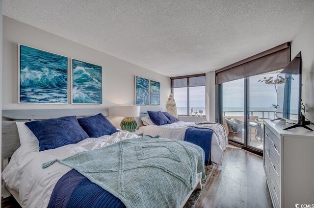 bedroom with floor to ceiling windows, a textured ceiling, and hardwood / wood-style flooring