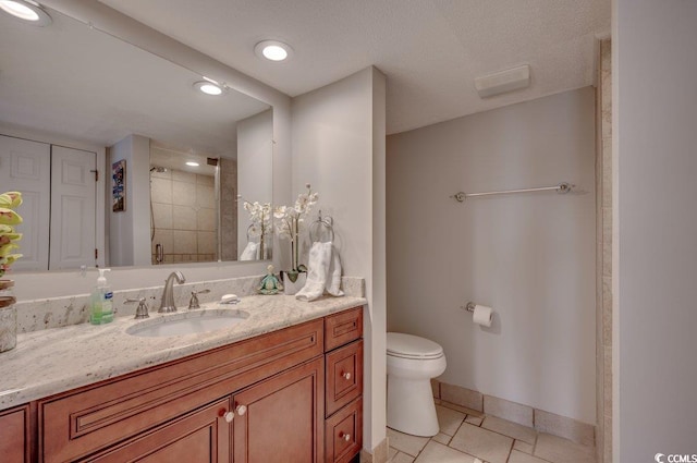 bathroom featuring a shower, vanity, a textured ceiling, tile patterned flooring, and toilet