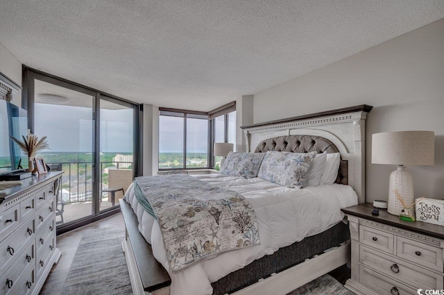 bedroom featuring access to outside, a textured ceiling, light wood-type flooring, and expansive windows