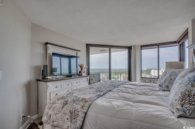 bedroom with a textured ceiling, a wall of windows, and access to outside