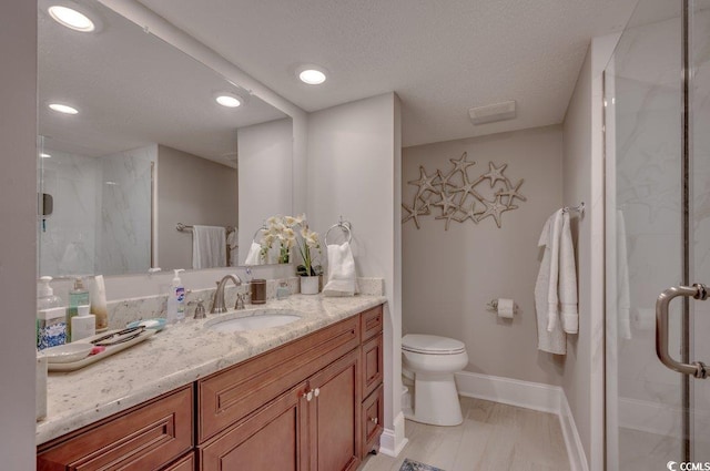 bathroom featuring vanity, a textured ceiling, toilet, and a shower with door