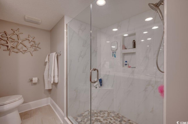 bathroom featuring a textured ceiling, toilet, and a shower with door