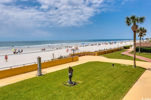 view of community with a yard, a water view, and a view of the beach