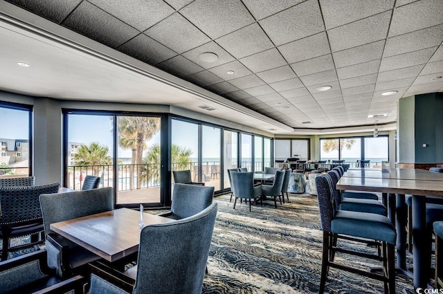 dining area with plenty of natural light, carpet floors, and a paneled ceiling