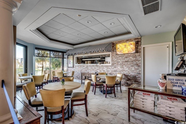 dining space with a raised ceiling and brick wall