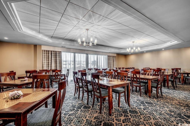 carpeted dining area featuring a tray ceiling and an inviting chandelier