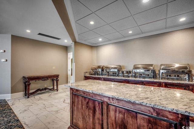 kitchen with a drop ceiling and light stone counters