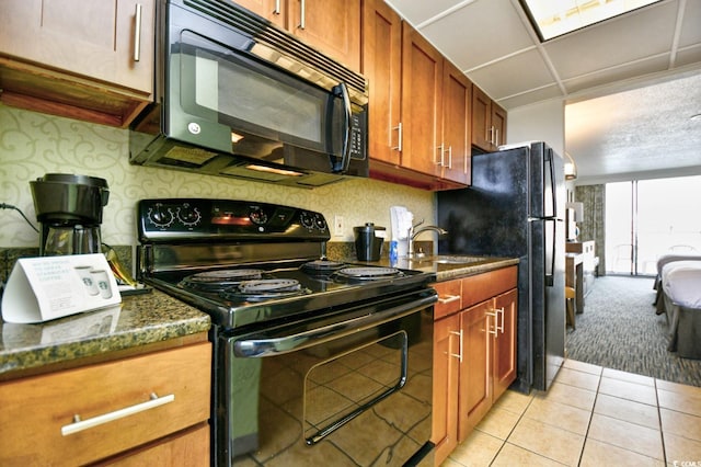 1105 S Ocean Blvd Unit 1044, Myrtle Beach, SC 29577 - kitchen with black appliances, light tile patterned flooring, brown cabinetry, light carpet, and dark stone countertops