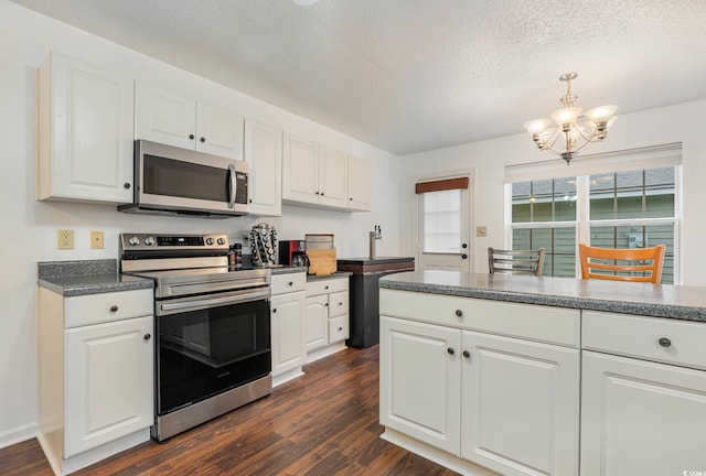 kitchen with a textured ceiling, dark wood-type flooring, a notable chandelier, white cabinetry, and appliances with stainless steel finishes