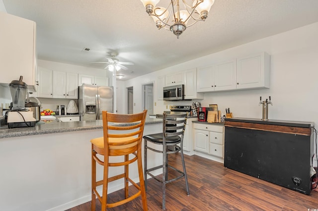 kitchen with white cabinetry, ceiling fan with notable chandelier, stainless steel appliances, a textured ceiling, and dark hardwood / wood-style floors