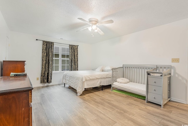 bedroom with a textured ceiling, light hardwood / wood-style floors, and ceiling fan