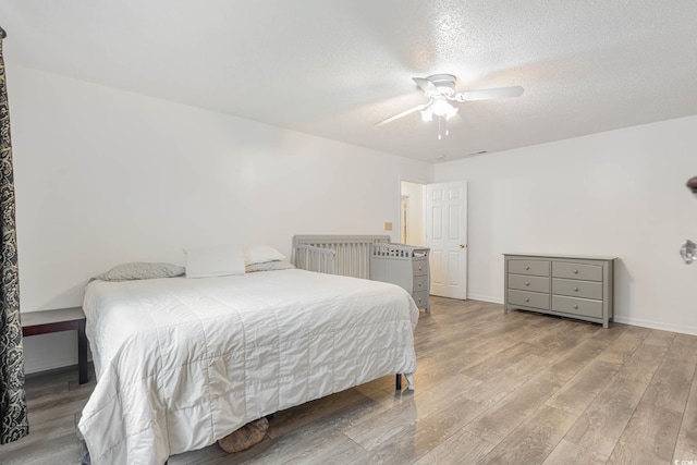 bedroom featuring light hardwood / wood-style floors, ceiling fan, and a textured ceiling