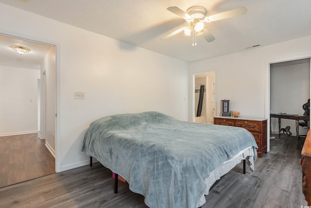 bedroom with ceiling fan, dark hardwood / wood-style floors, and a textured ceiling