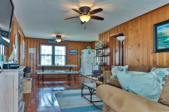 living room featuring wood walls, dark wood-type flooring, and ceiling fan