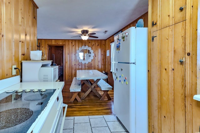 interior space featuring ceiling fan, wood walls, white appliances, white cabinetry, and light wood-type flooring